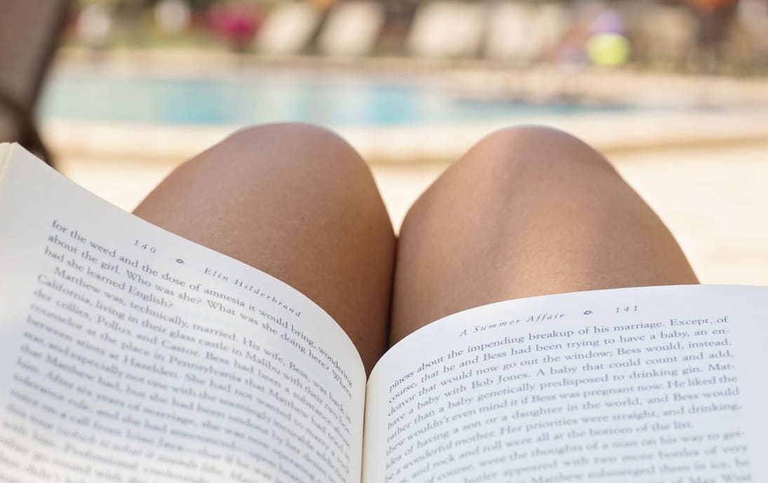 Reading a book by a sunny swimming pool