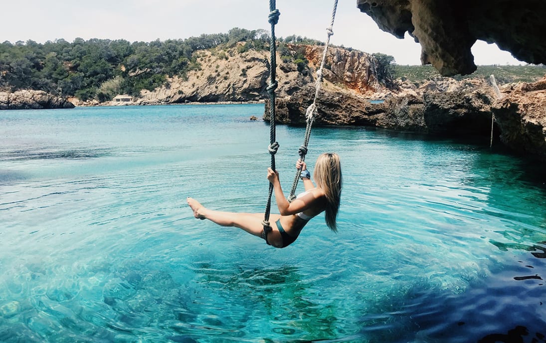 Rope swinging over clear waters in Ibiza