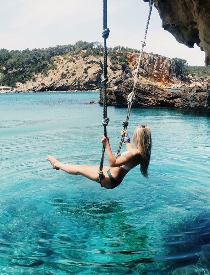 Rope swinging over clear waters in Ibiza